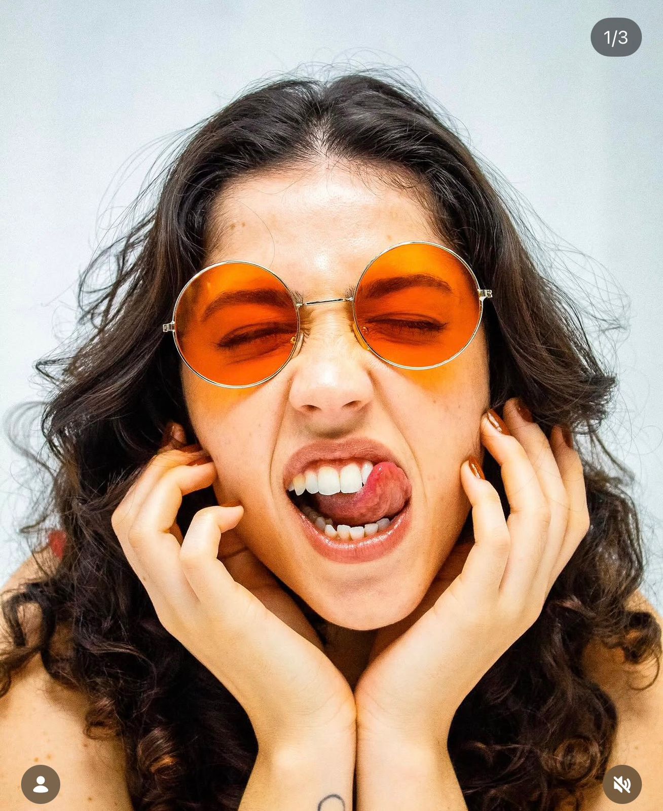 Retrato da artista pop Binova com óculos redondos laranja